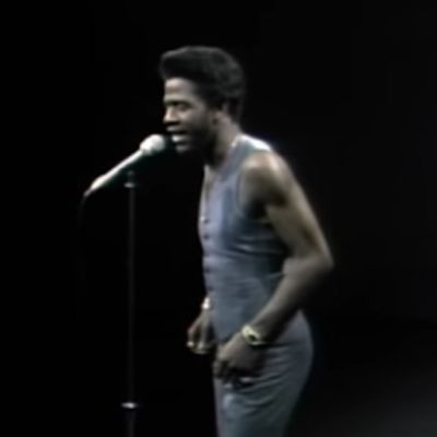 Al Green is singing in front of mic as he can be seen wearing a sleeveless vest.